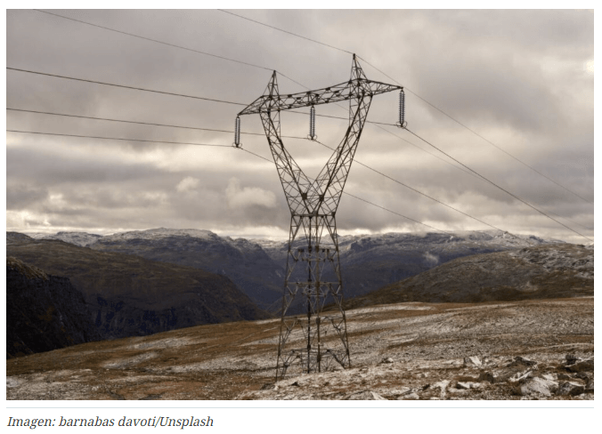 Torre de transmisión en zona de incendios forestales con cielo rojizo.