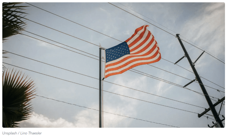 Torres de transmisión con nuevos conductores instalados sobre corredor existente con la bandera de Estados Unidos.