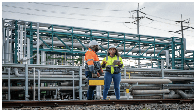 Dos persona al frente de una instalación de tuberías y una red eléctrica.