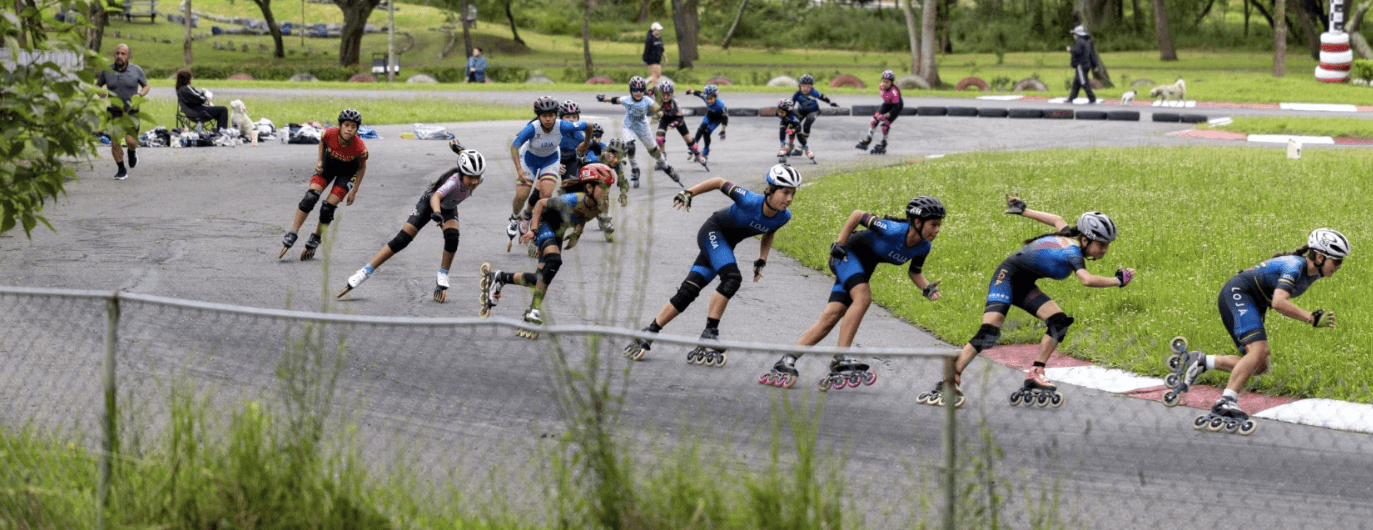 Parque urbano con corredores verdes y pista de patinaje con varias personas.