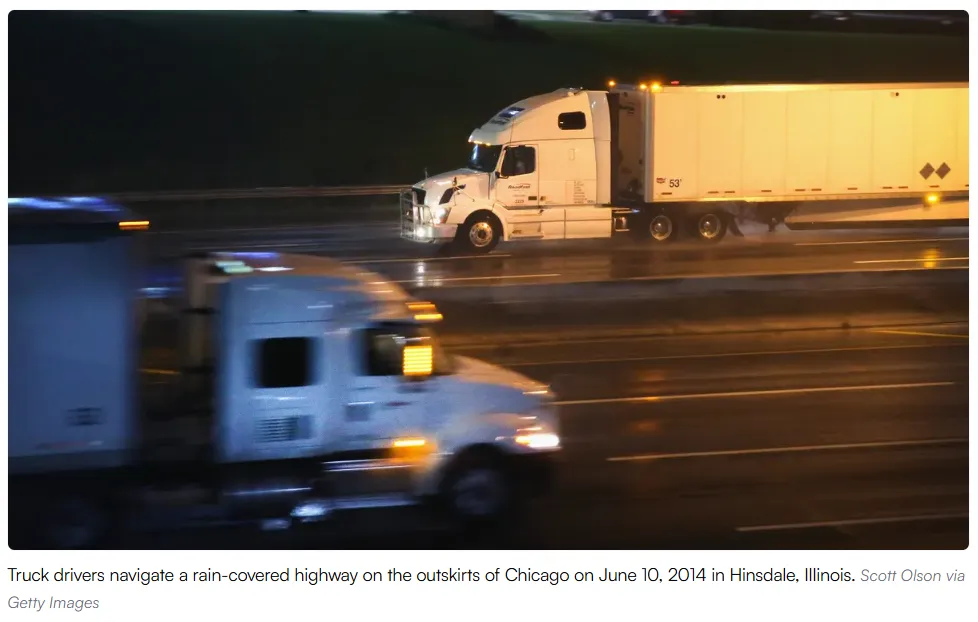 Camioneros en camión blanco circulan por una autopista mojada en las afueras de Chicago de noche.