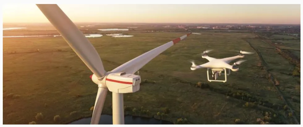 La imagen muestra un dron realizando mantenimiento o inspección en un aerogenerador (turbina eólica).