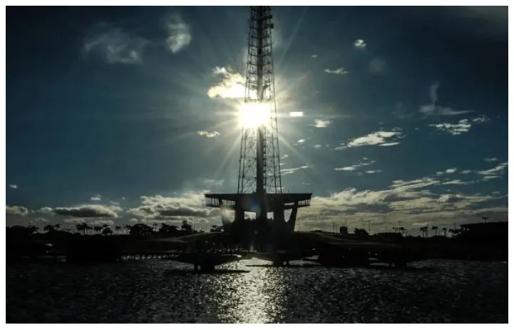 La imagen muestra la Torre de Televisión de Brasilia durante un amanecer o atardecer, destacando su silueta contra el sol.