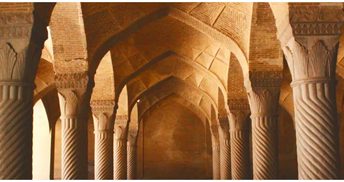 La imagen muestra el interior de la Mezquita Vakil en Shiraz, Irán. La estructura destaca por su shabestan (sala de oración) sostenida por 48 columnas monolíticas talladas en espiral y techos abovedados de ladrillo.