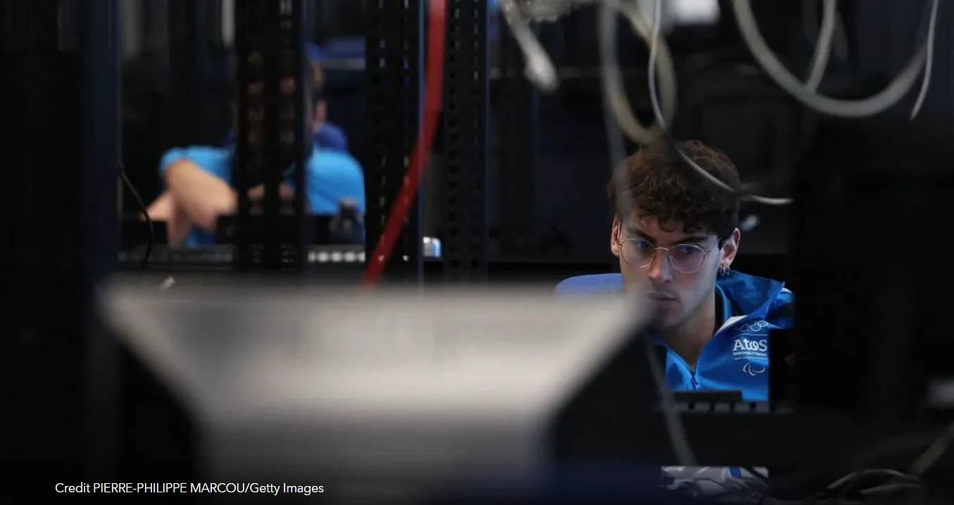 La imagen muestra a un empleado de la empresa Atos trabajando en un centro de ciberseguridad