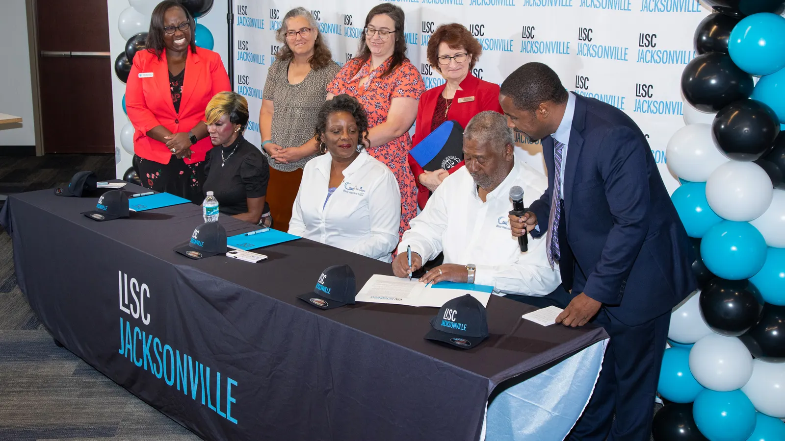 Tres personas firman documentos patrimoniales en un foro de planificación patrimonial organizado por Local Initiatives Support Corp. Jacksonville y Family Foundations del noreste de Florida en octubre de 2023.